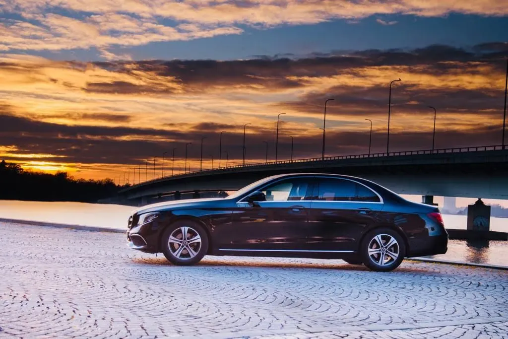 Musta Mercedes-Benz E-sarja auringonlaskussa