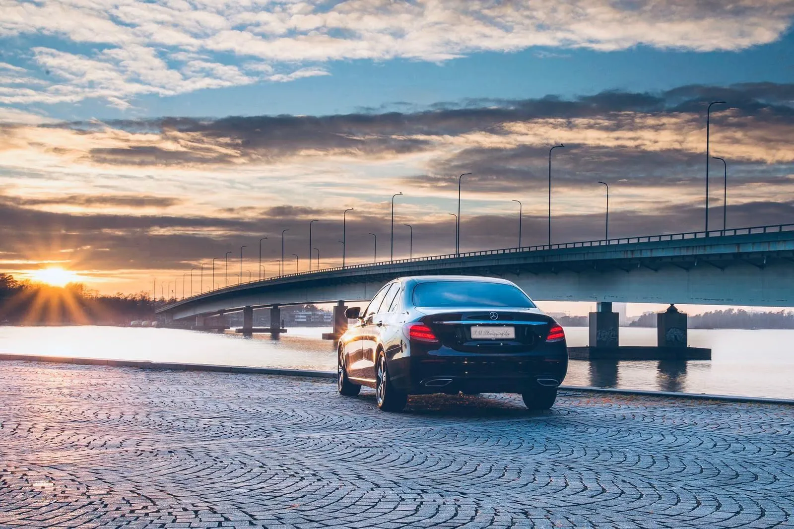 Mercedes-Benz E-sarja sillan edustalla auringonlaskussa
